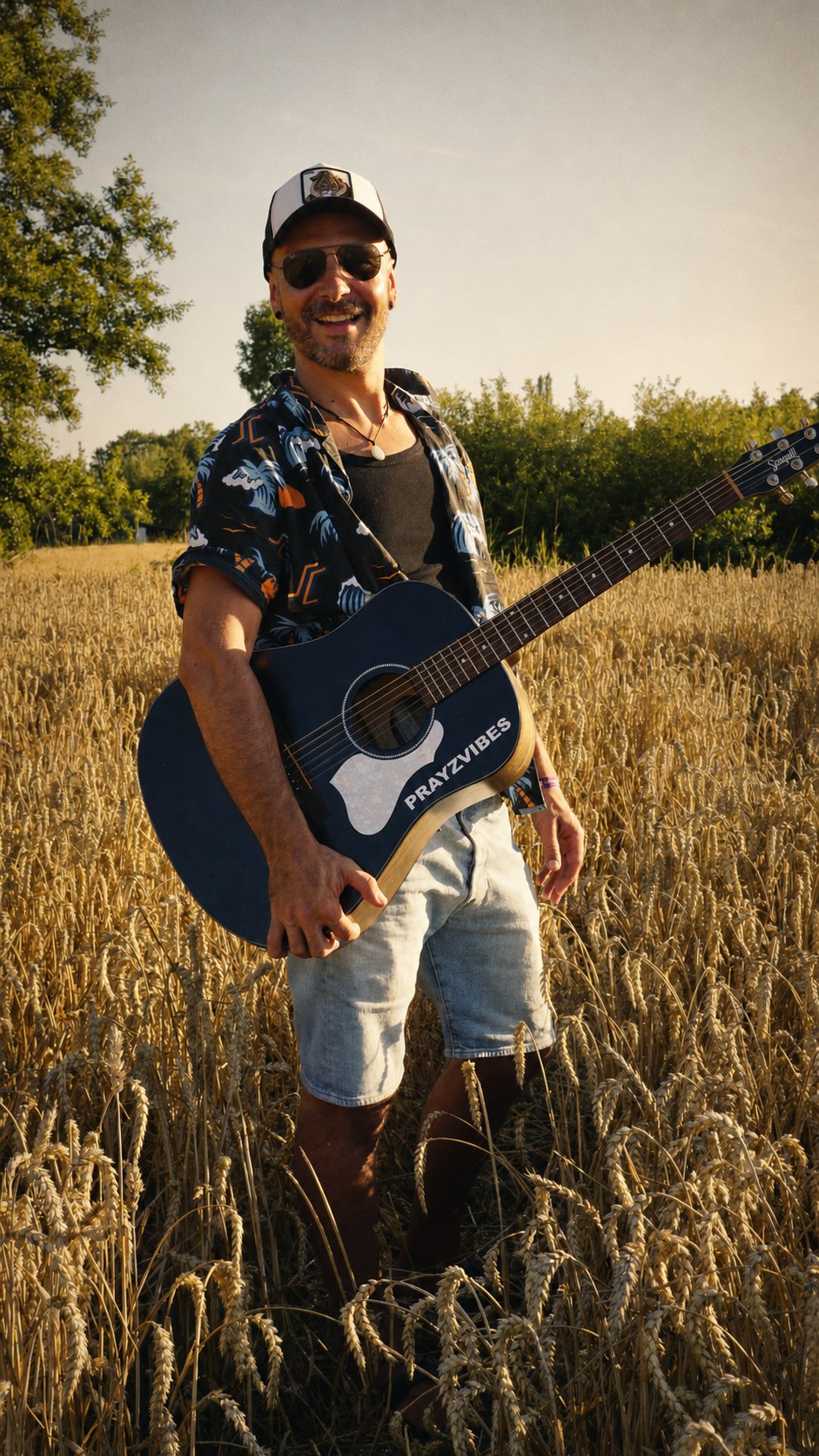 PRAYZVIBES debout avec une guitare acoustique dans un champ